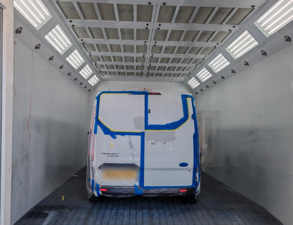 Van rear doors masked up in the paint booth, ready for refinishing