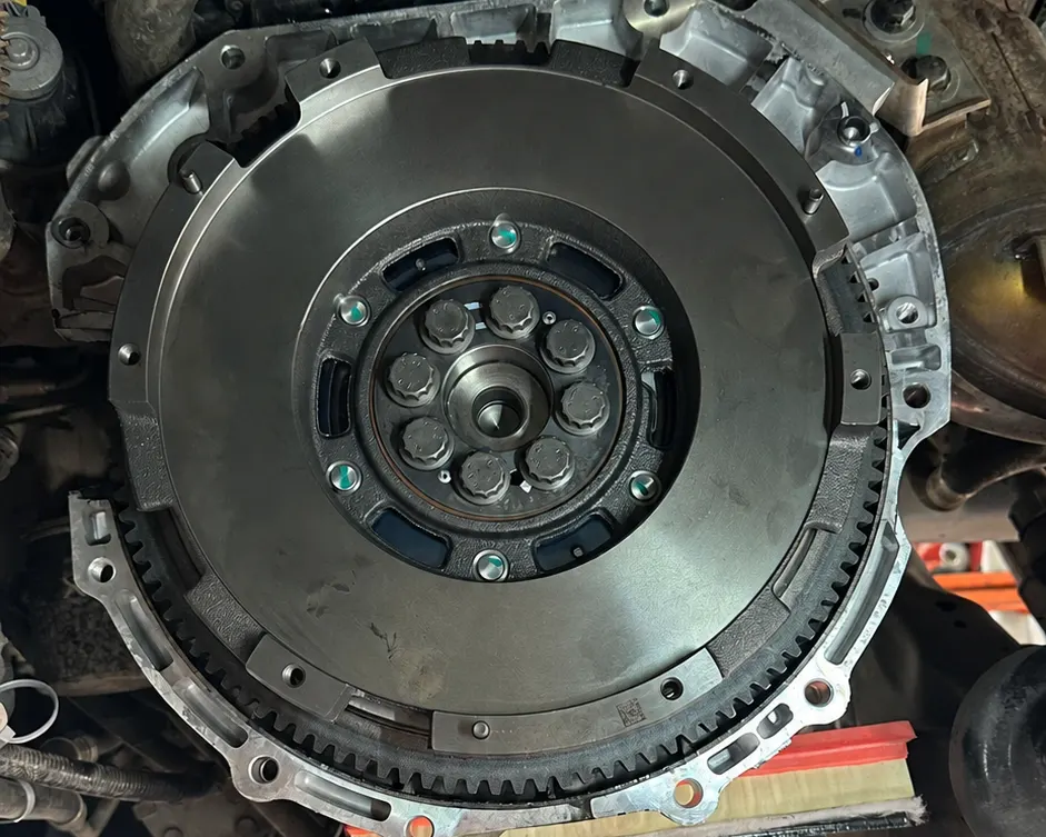 A dual-mass flywheel on a car at NRH Autoworks in Bray, with the gearbox lowered for a clutch replacement